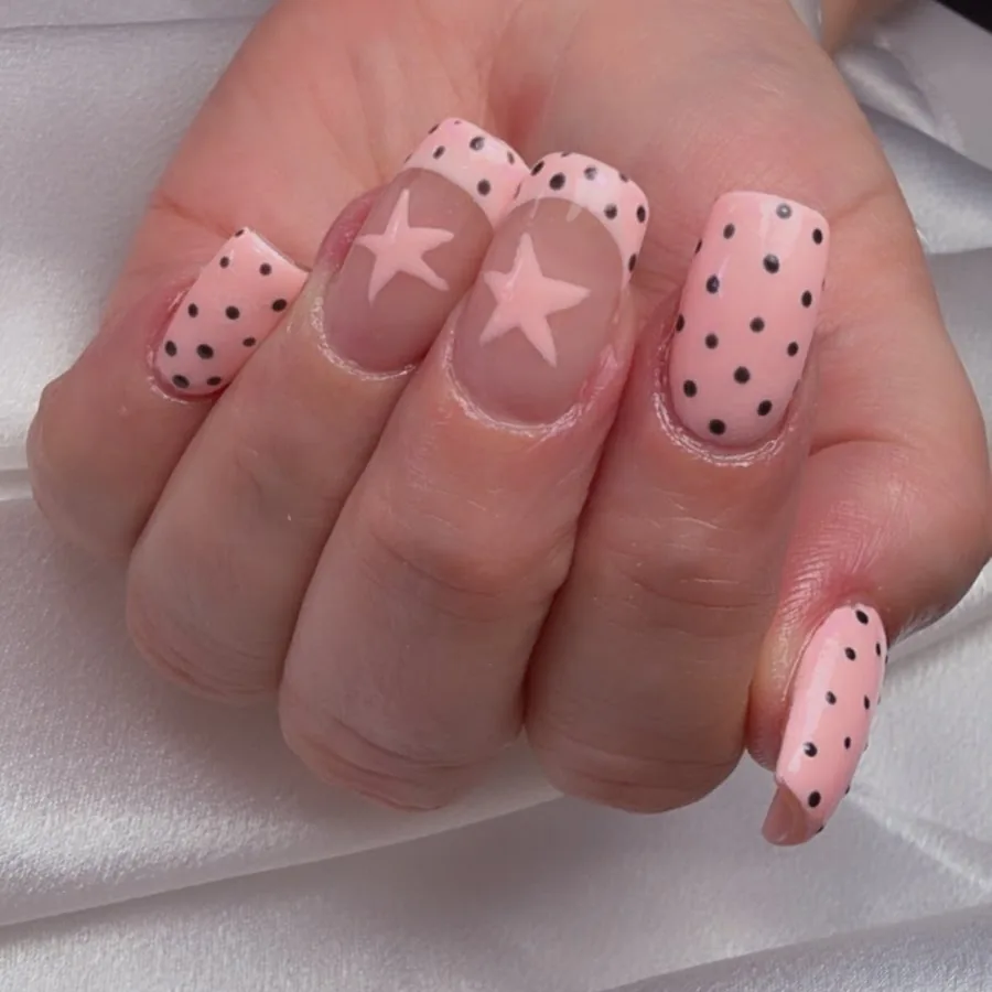 Blush pink acrylic nails with black polka dots and star accents at Yudy's Queen Nails in Palm Beach Gardens